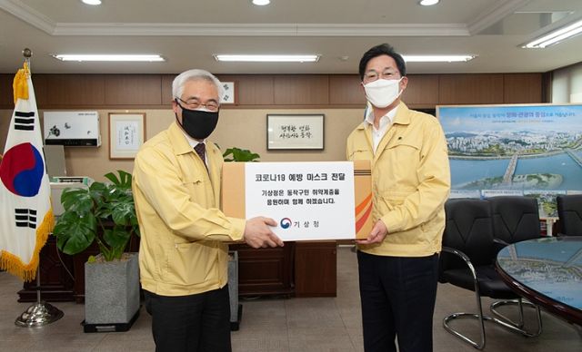 김종석 기상청장(왼쪽)이 이창우 동작구청장에게 직원들이 자발적으로 모은 마스크를 전달하고 있다.