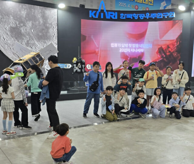 한국항공우주연구원이 전시한 누리호 및 인공위성 모형 앞에서 기념촬영하는 단체 관람객들.