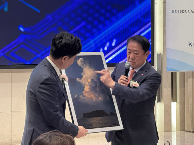 오경수 KISIA 명예회장(오른쪽)이 김진수 KISIA 신임 회장에게 선물하는 사진을 설명하고 있다.